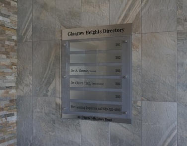 Stand-off building directory sign with glass face, engraved brushed aluminum nameplates with room numbers